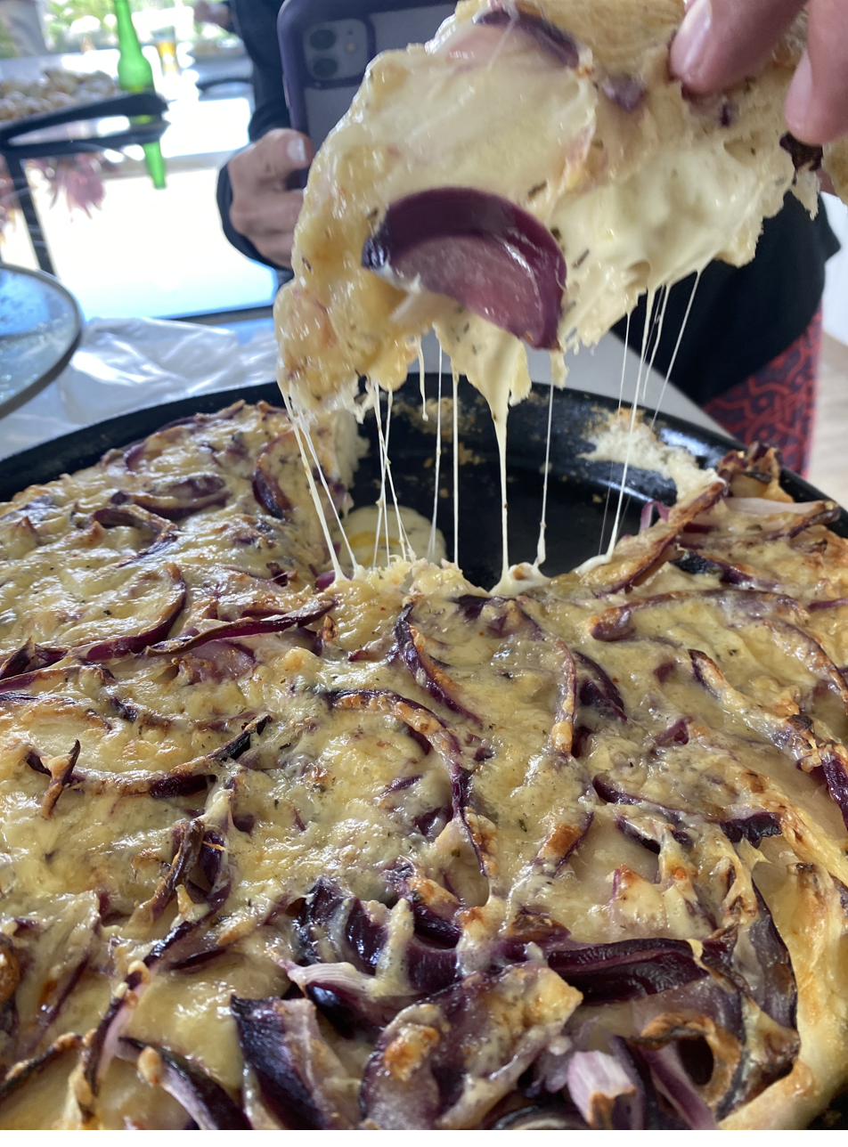 Focaccia con queso fundido y cebolla morada, tirando queso