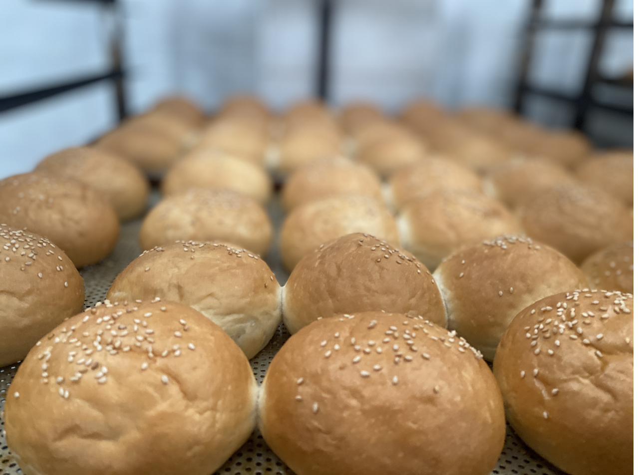 Panes de hamburguesa con sésamo recién horneados en producción